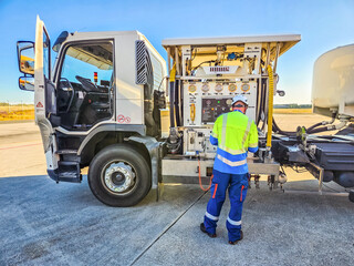 Airport worker refueling aircraft from fuel truck on sunny tarmac scene. High quality photo