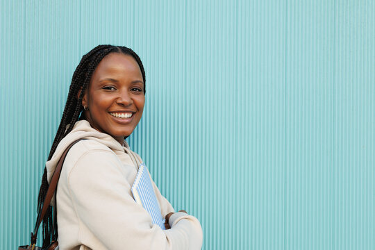 Smiling student holding books against blue background. Copy space.