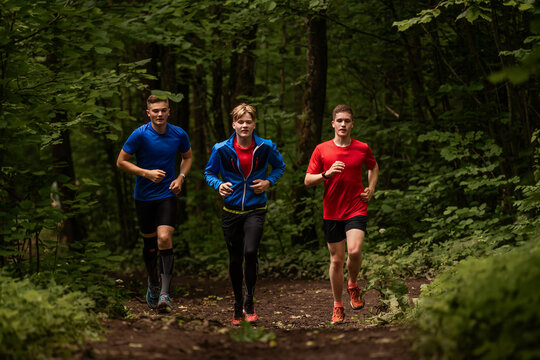 group of young boys run together on a forest trail
