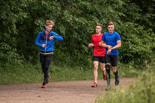 Three young boys running on a trail in a park
