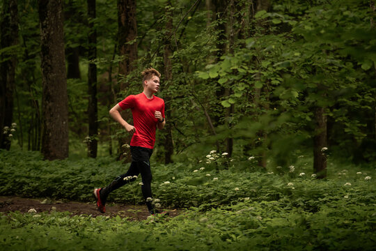 young boy running cross country in summer forest