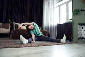 Young woman practicing flexibility exercises at home during the afternoon