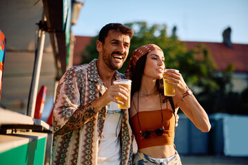 Happy couple enjoying in cold beer during summer music festival.