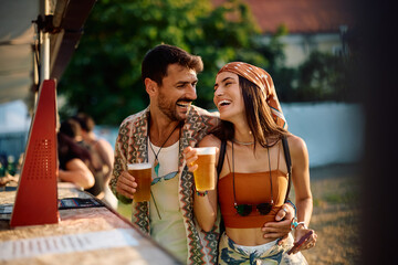 Carefree couple buying beer during open air music festival in summer.