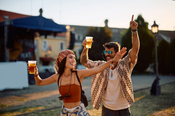 Happy couple of festival goers having fun and dancing during music concert in summer.