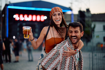 Carefree couple piggybacking while attending summer music festival.