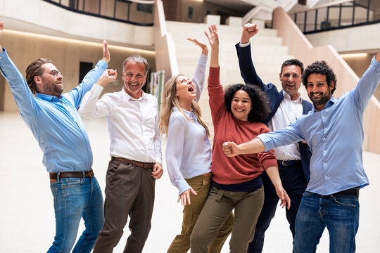 Cheerful multiracial business colleagues celebrating success in lobby