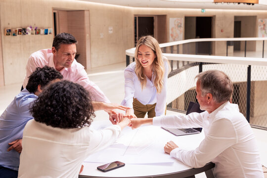 Smiling businesswoman doing fist bump with colleagues in corridor