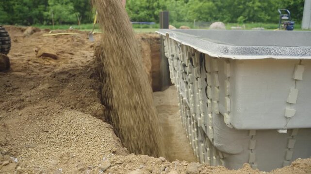 Side view of crushed gravel poured to backfill fiberglass pool install in backyard.
