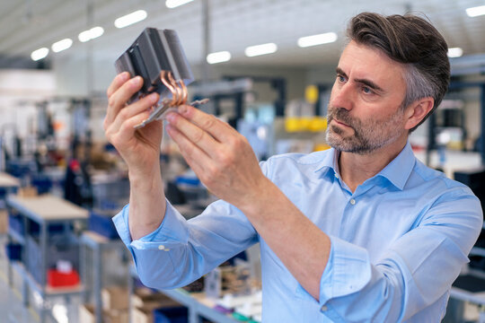Businessman examining machine part in industry