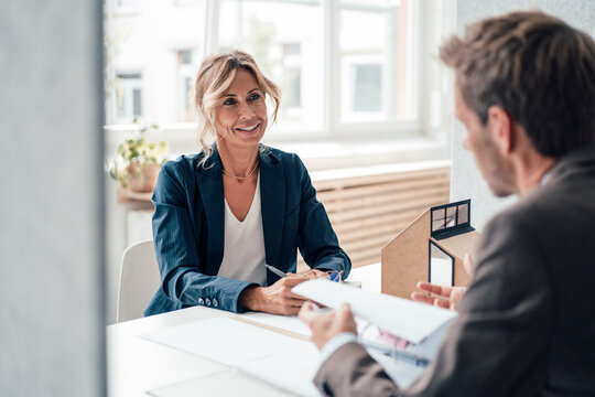 Real estate agent and client discussing with each other at office