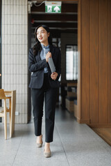 Fototapeta premium Businesswoman walking in office corridor holding tablet computer