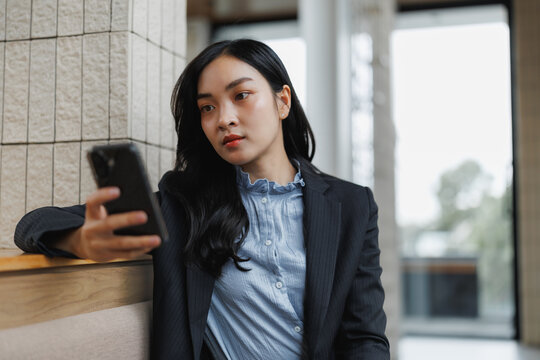 Businesswoman using smartphone in modern office lobby
