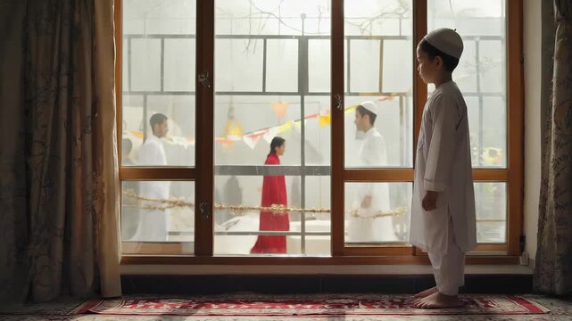 A young boy dressed in a white kurta and skullcap gazes out the window, waiting with excitement as neighbors celebrate in colorful festive attire
