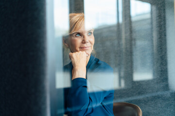 Contemplative businesswoman with hand on chin in soundproof cabin