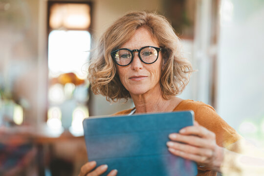 Mature woman using tablet PC sitting at home