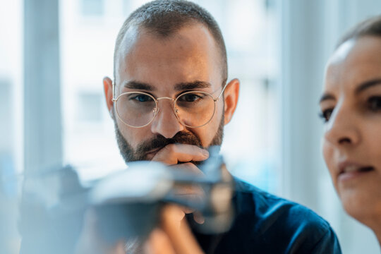Thoughtful businessman with colleague looking at drone in home office