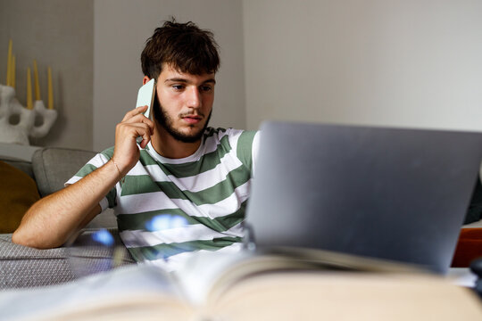 Teenage boy studying at home, using his smartphone