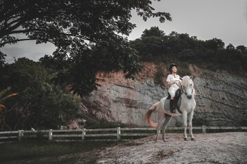 Young Girl Riding White Horse on Scenic Landscape in Nature