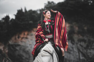 Young Woman in Traditional Attire Riding Horse in Natural Landscape