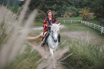 Young rider on white horse in traditional attire on scenic trail