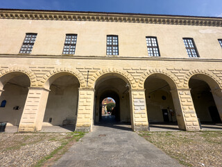 The grand historic Visconti Castle of Melegnano stands majestically behind a lush green park on a sunny day.