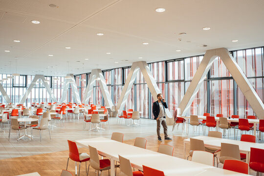 Businessman talking on phone standing amidst chairs and tables