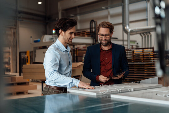 Mature businessman with colleague touching wood in industry