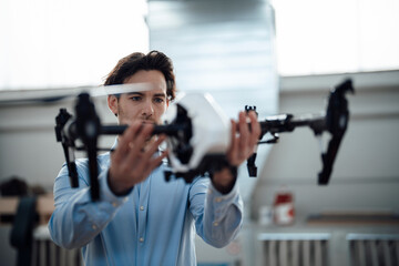 Young businessman examining drone in factory