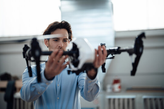 Young businessman examining drone in factory