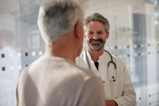 Smiling senior doctor talking to man in hospital