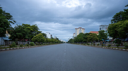 A Serene Urban Landscape: An Empty City Road Flanked by Lush Trees and Modern Architecture Under a Dramatic Sky