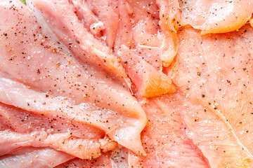 Raw chicken fillet marinated with seasonings close-up. Background with the texture of raw chicken meat. The process of making cordon bleu.