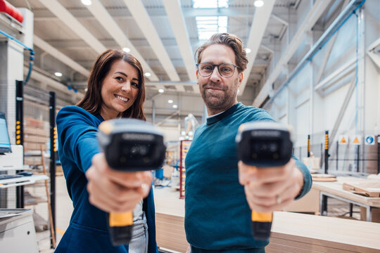 Smiling colleagues with bar code readers standing in industry