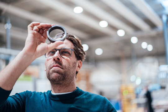 Businessman examining metal circle in industry