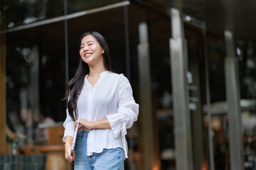 Smiling businesswoman holding laptop walking in urban city