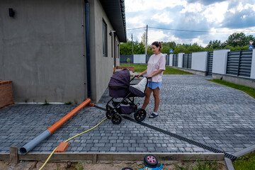 young mother with a stroller doing her daily chores near her private house