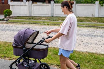 young mother with a stroller doing her daily chores near her private house