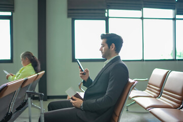 Side of mature businessman sitting in a modern waiting area with a bored expression. Corporate...