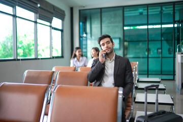 A businessman talking on the phone with a serious and expressionless face, sitting in a modern...