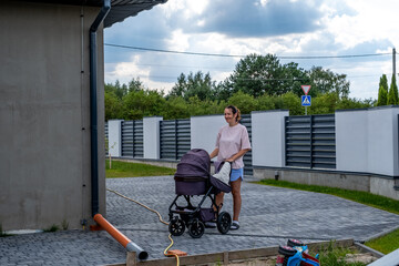 young mother with a stroller doing her daily chores near her private house