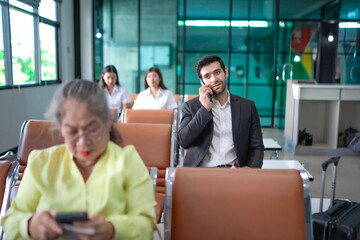 Man in business attire making a phone call in a quiet airport area, with a blank face showing calm...