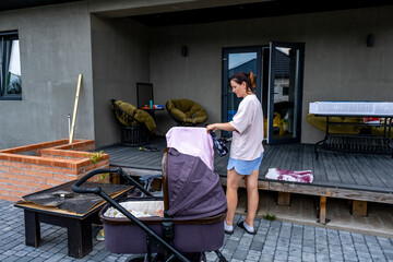 young mother with a stroller doing her daily chores near her private house