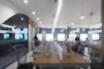 Blurred modern office interior with open space design. Rows of workstations and minimalistic lighting fixtures create a contemporary business environment.
