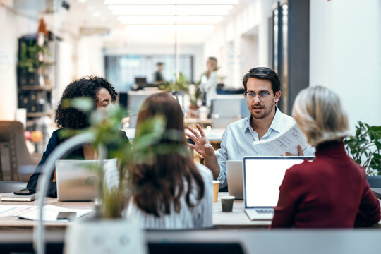 Businessman discussing with colleagues at desk
