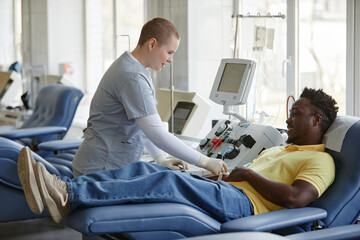 Healthcare worker assisting donor reclining on couch at blood donation center