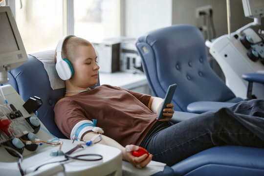 Woman donating blood and listening to music