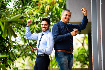 Indian business professionals with tablet collaborating outside modern corporate building