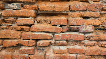 Close-up of an aged, rustic red brick wall with uneven mortar, showing texture, decay, and historical construction character.