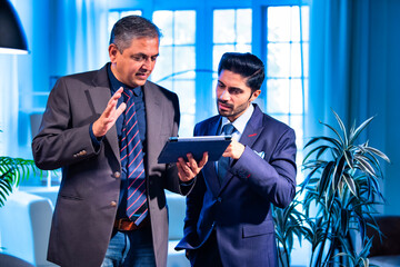 Indian businessmen collaborating on tablet for project planning in professional office space
